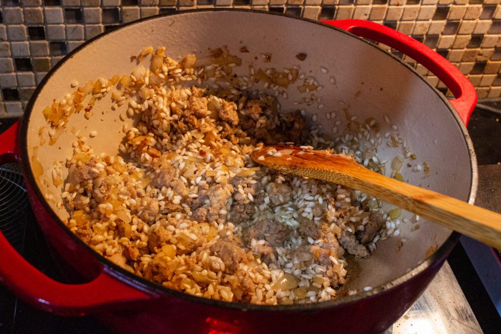 Toast the arborio rice with the caramelized meat and onions